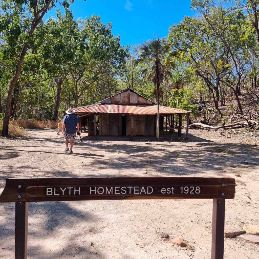 Man in a hat walking towards a small shed on a sunny day, Blyth Homestead in Litchfield National Park