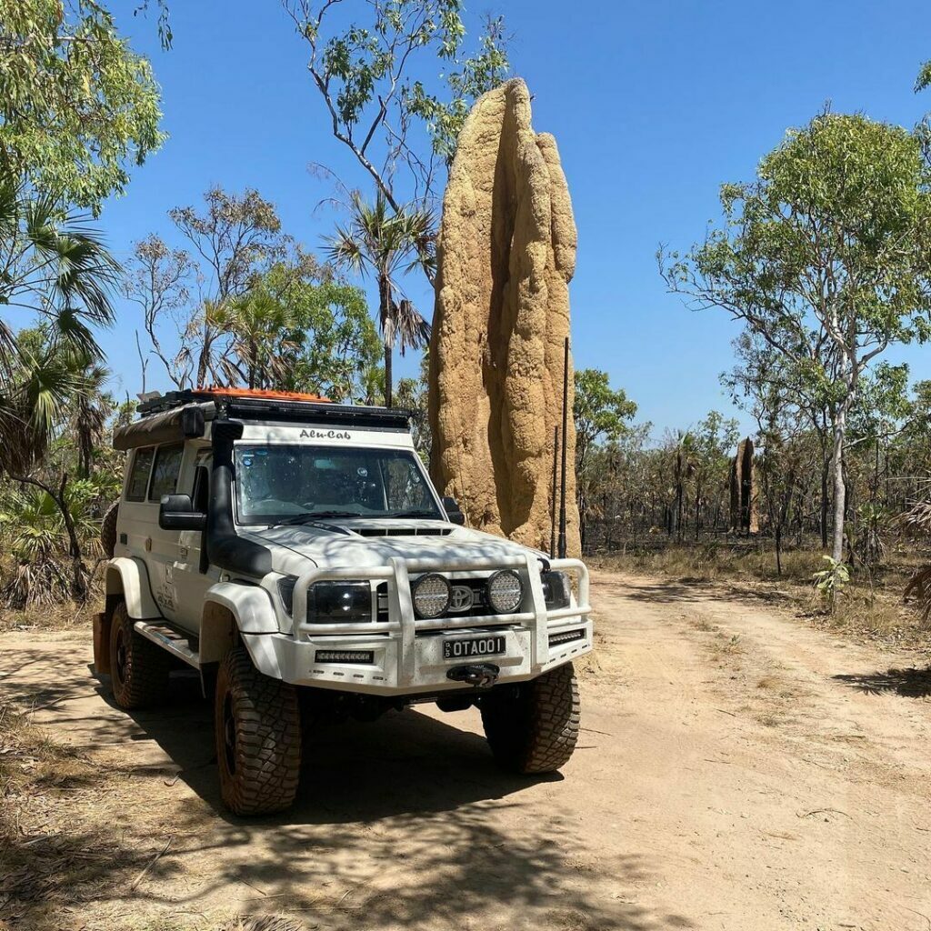 White 4wd vehicle parked next to a magnetic termite mound at litchfield national park