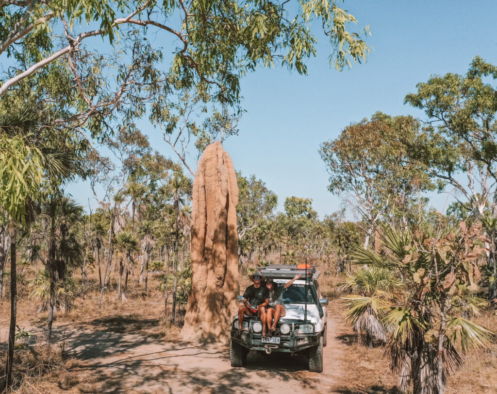 Couple sitting on top of a 4wd vehicle parked next to a termite mound in Litchfield National Park, Litchy
