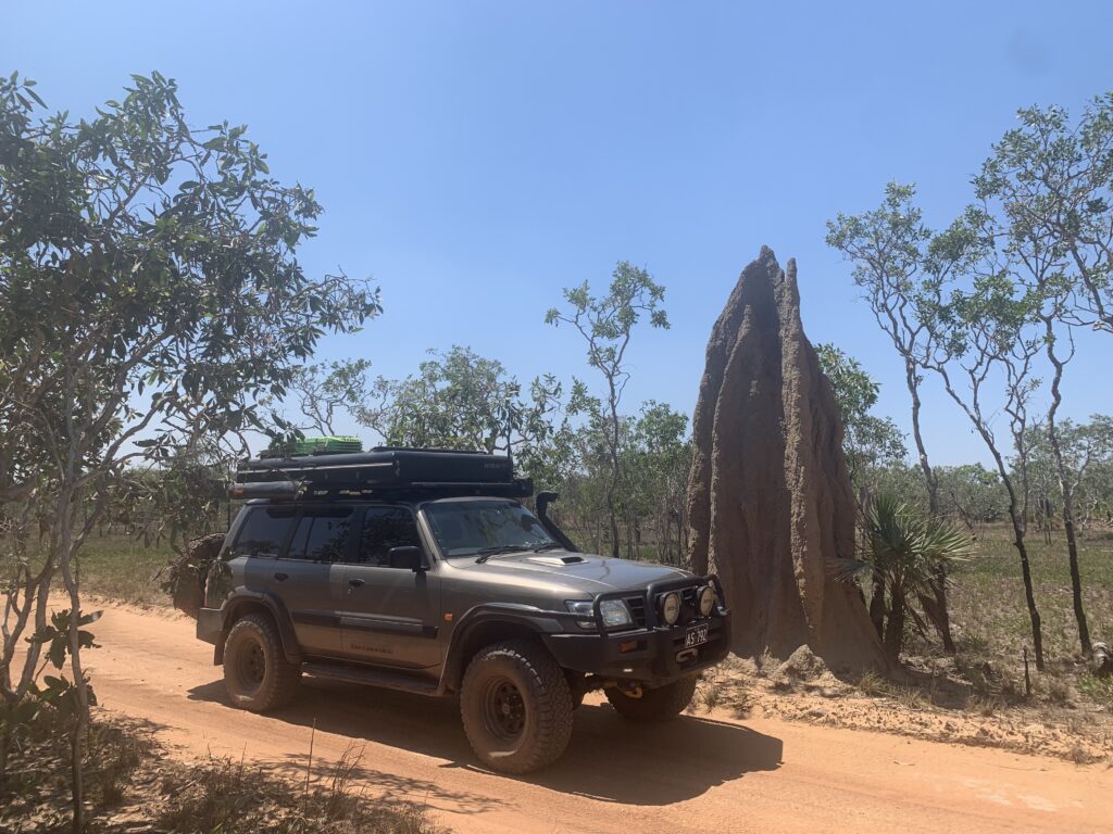 black 4wd vehicle parked next to a big termite mound cathedral in litchfield national park