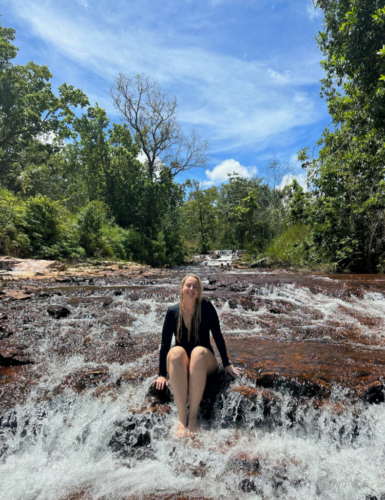 young blond woman sitting in a small waterfall in litchfield national park in the northern territory